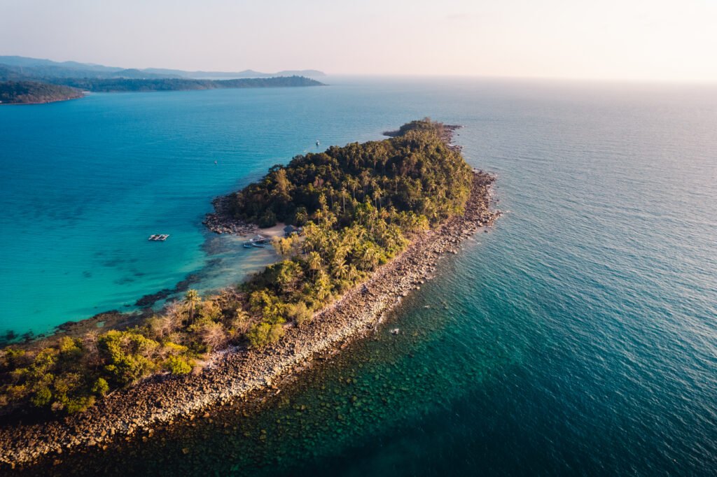 Scenic view of the Andaman Islands featuring turquoise waters, white sandy beaches, and lush green palm trees under a bright tropical sky.