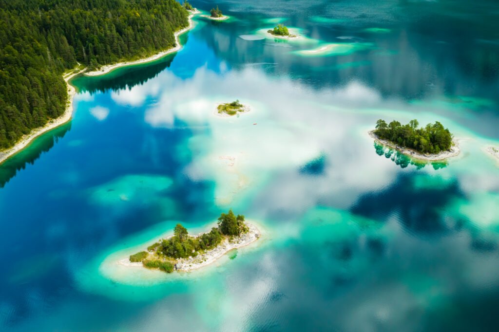 amazing islands with trees on a lake with turquoise water and clouds reflection